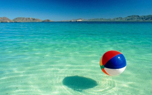 Beach ball floating on water at beach